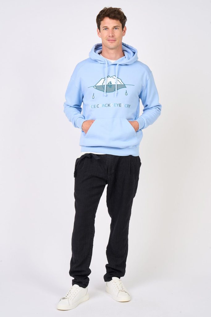 Sky blue hoodie with white iceberg print worn by male model with navy blue trousers